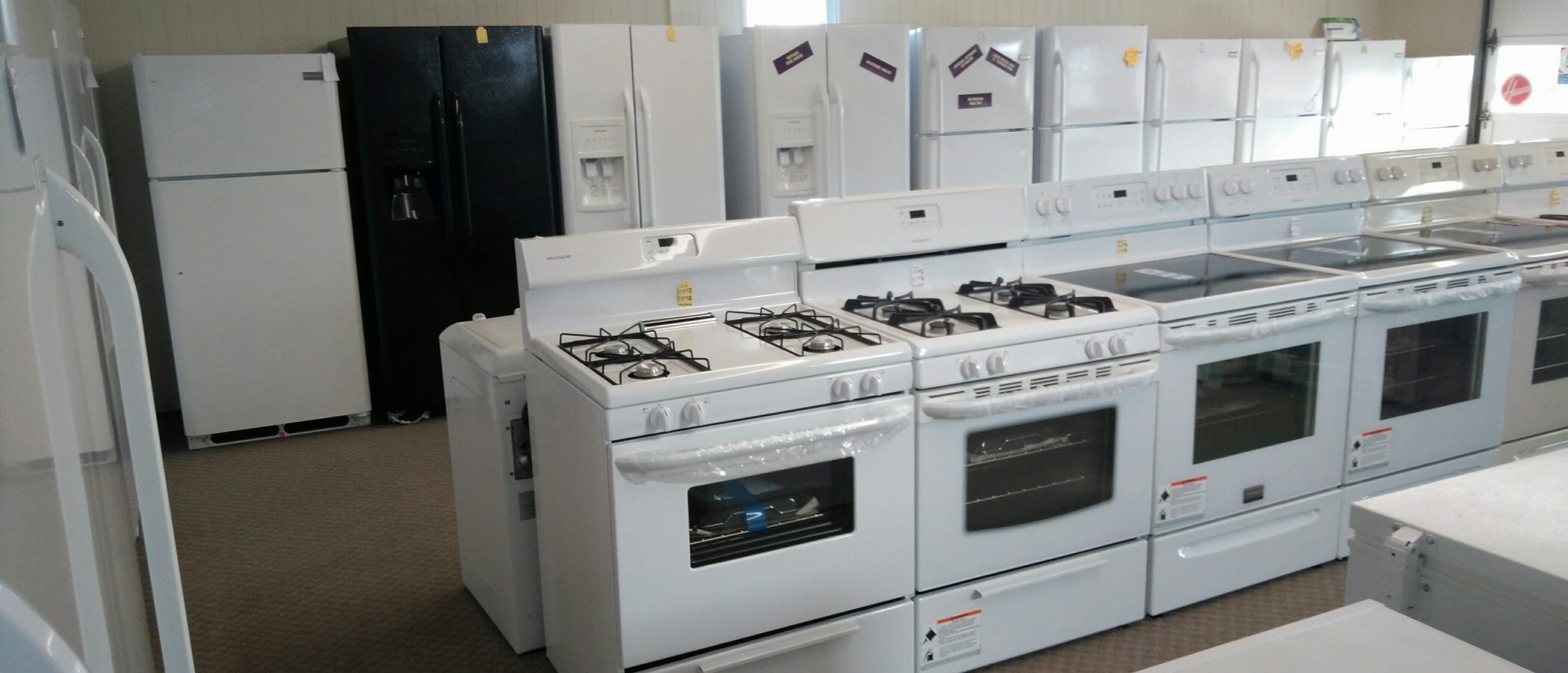 Many stoves and refrigerators in in orderly rows inside the Christman Appliances store